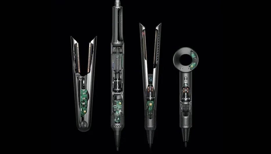 Vier Dyson-Styler und -Heißluftfön-Modelle in Schwarz und Silber mit sichtbarer Elektronik und internen Komponenten auf schwarzem Hintergrund – darunter zwei Lockenstäbe mit Gleitaufsätzen, ein vertikaler Heißluftfön und ein kompaktes Handgerät mit digitalem Display.