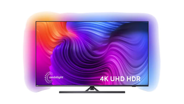 Ein Flachbildfernseher mit farbenfrohem Display steht auf einem schwarzen Standfuß vor einem weißen Hintergrund.