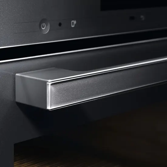 Nahaufnahme eines schwarzen Backofens mit einem silbernen Griff und Bedienfeldern.