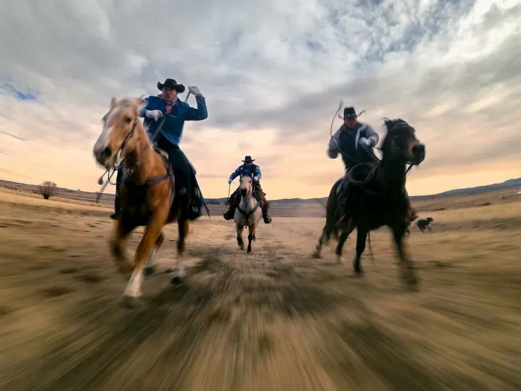 Ein Foto, das mit der GoPro Mission 1 Pro aufgenommen wurde, zeigt drei Männer auf Pferden, die auf die Kamera zugaloppieren.