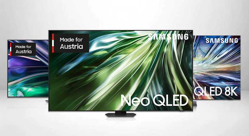 Drei Samsung Fernseher stehen auf einem hellgrauen Untergrund. Der mittlere Fernseher zeigt ein grünes, abstraktes Muster und den Schriftzug "Neo QLED".