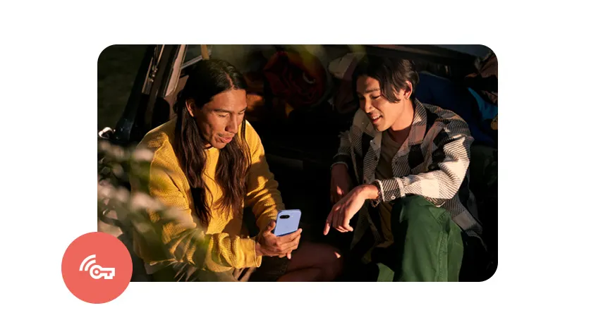 Zwei Personen sitzen im Freien, eine Person hält ein blaues Smartphone in der Hand. Der Hintergrund ist unscharf.