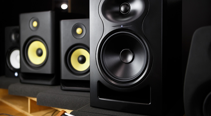 4 große schwarze Lautsprecher, die hintereinander versetzt aufgereiht sind