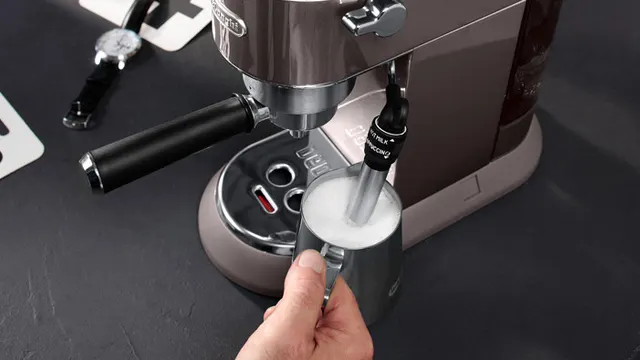 Eine Kaffeemaschine schäumt Milch in einem silbernen Krug auf einem dunklen Tisch auf.