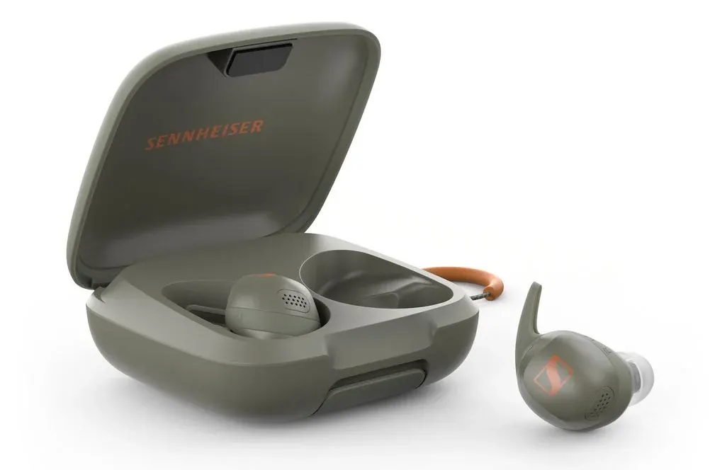 Das geöffnete Ladecase der Sennheiser Momentum Sport1 in Olivgrün liegt auf weißem Hintergrund. Ein Earbud liegt im Case, ein weiterer liegt davor.