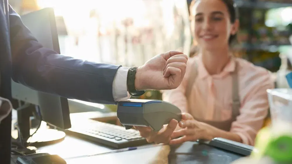 ein Mann im Anzug bezahlt kontaktlos mit seiner Smartwatch