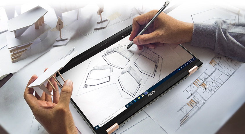 Eine Person zeichnet mit einem Stift auf einem Acer Laptop, neben einem Architekturmodell und Plänen.