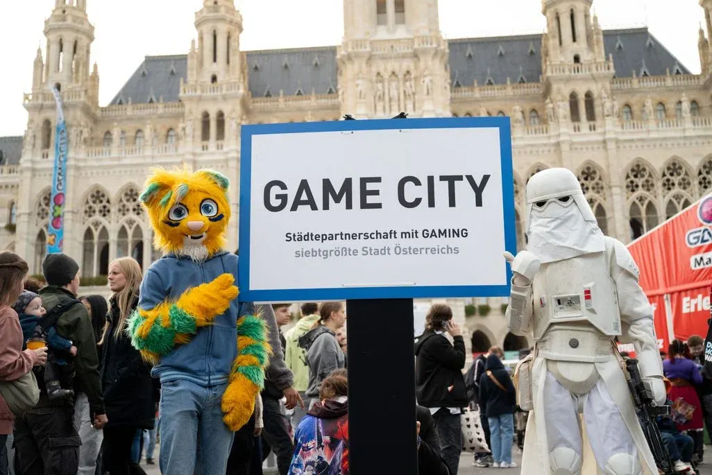 Cosplayer vor einem GAME CITY "Ortsschild"