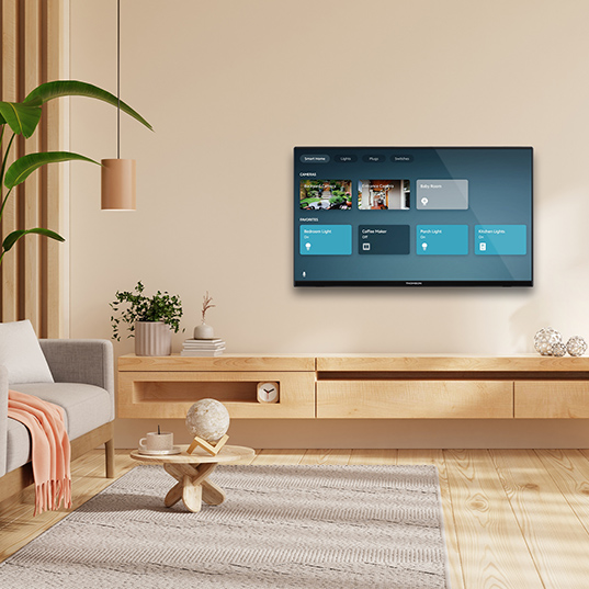 Ein Wohnzimmer mit einem Fernseher an der Wand über einem Holzschrank, einem Teppich und einem Sofa.