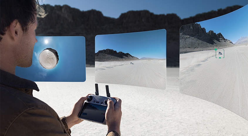  Person steuert DJI Drohne mit Fernbedienung in Wüstenlandschaft, drei schwebende Displays zeigen verschiedene 360°-Luftaufnahmen.