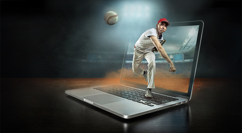 Ein silberfarbener Laptop steht auf einer dunklen Oberfläche, wobei ein Baseballspieler aus dem Bildschirm springt. Ein Baseball schwebt über dem Bildschirm.