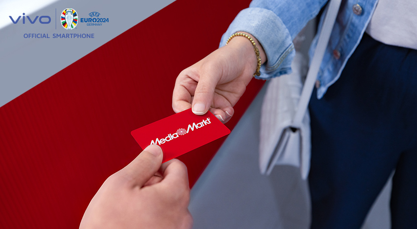 Eine rote MediaMarkt Karte wird zwischen zwei Händen ausgetauscht, im Hintergrund Vivo und Euro 2024 Logos.