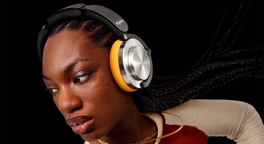 Nahaufnahme von Kopfhörern mit gelben und silbernen Ohrmuscheln vor schwarzem Hintergrund.