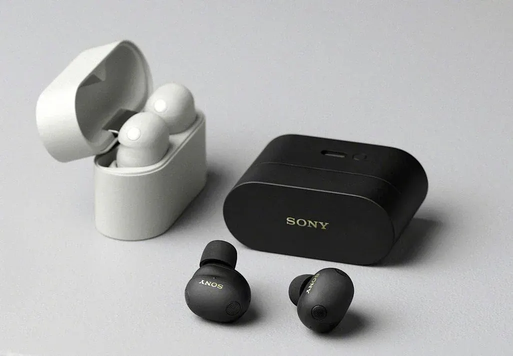 Zwei Paar kabellose Sony In-Ear-Kopfhörer mit Ladecases. Links ein hellgraues Paar im geöffneten Case, rechts ein geschlossenes schwarzes Case, vor dem die zwei schwarzen Kopfhörer liegen.