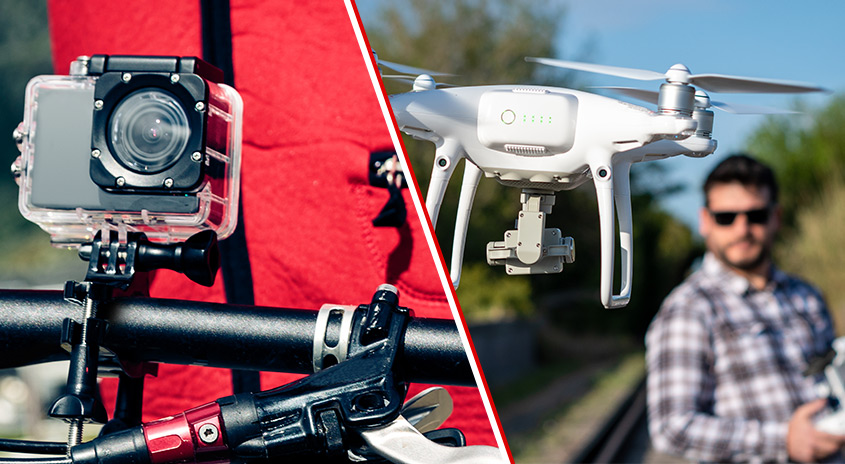 Action-Cam am Fahrradlenker und schwebende Kamera-Drohne im Einsatz, im Hintergrund ist ein Mann im Freien zu sehen, der die Drohne lenkt.