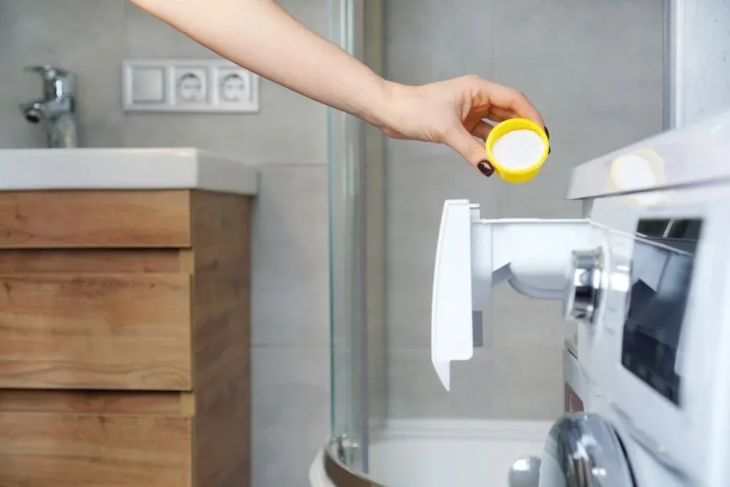 Eine Person füllt Waschpulver in eine Waschmaschine ein