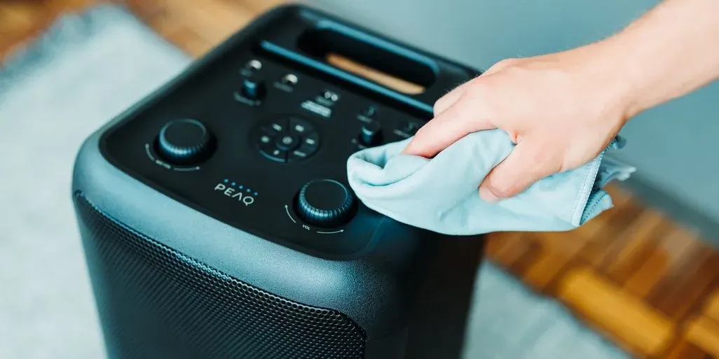 Ein Lautsprecher wird mit einem Microfasertuch gereinigt.