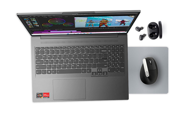 Draufsicht: grauer Laptop mit geöffnetem Bildschirm, schwarze Maus auf Mauspad, Ohrhörer mit Ladecase.