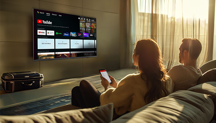 Aufnahme eines Zimmers mit einem Fernseher, der an der Wand montiert ist, und einer schwarzen Kiste auf einem Regal.