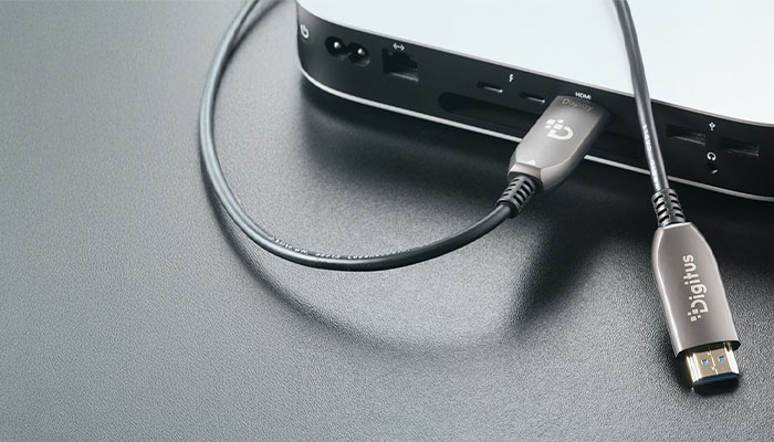Nahaufnahme eines metallgrauen Digitus Kabels, das in den HDMI-Anschluss eines silbernen Mini-PCs eingesteckt ist.