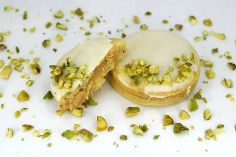 Zwei Kekse mit Pistazien, Erdnuss und weißer Schokolade mit gehackten Pistazien überstreut