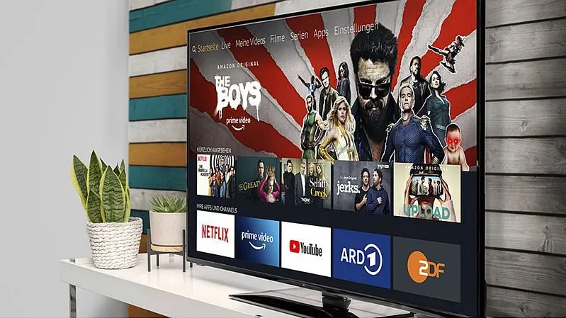 Ein Fernseher steht auf einem TV-Möbel und zeigt Serien und Apps im Startbildschirm.