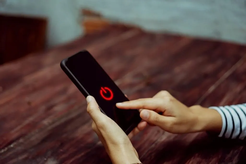 Person haelt Smartphone mit rotem Einschaltzeichen auf dem Display
