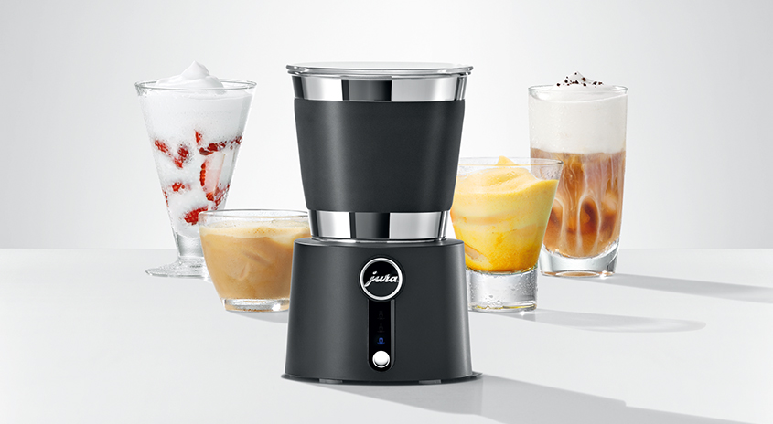 Ein Milchaufschäumer von Jura mit Getränken in Gläsern auf einem weißen Tisch vor weißem Hintergrund.