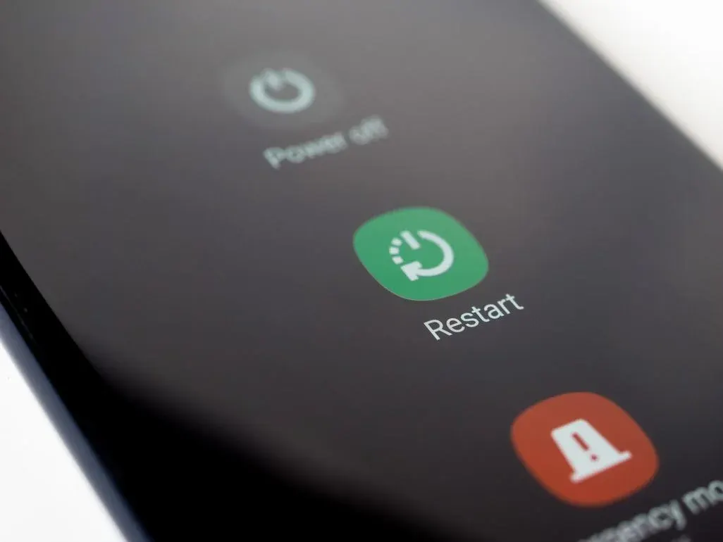 Nahaufnahme eines Smartphone-Bildschirms mit "Ausschalten", einem grünen "Neustart"-Button und einem roten "Notfallmodus"-Button.