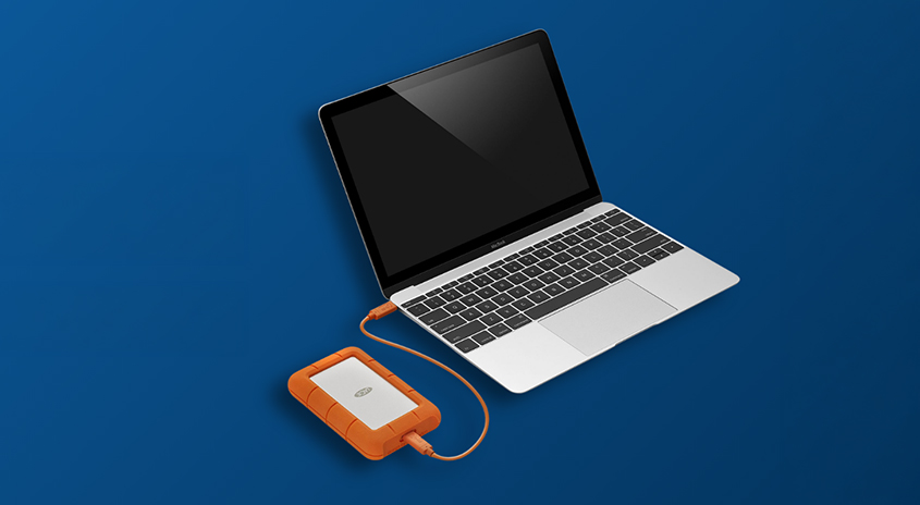 Abbildung: Notebook mit angesteckter Lacie Festplatte, blauer Hintergrund. 