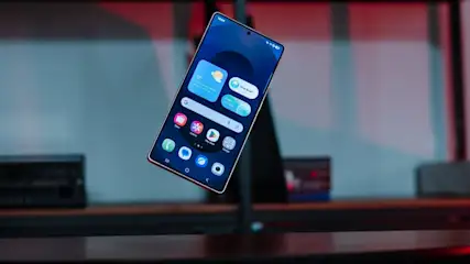 Samsung Galaxy S25 Ultra Smartphone schwebt über einem Tisch, Display mit App-Symbolen ist sichtbar.