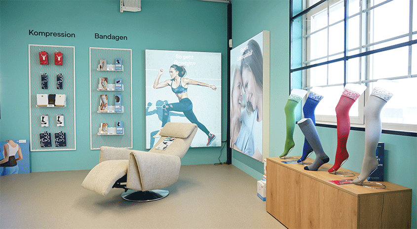 Ein Geschäft mit Kompressionsprodukten: Regale mit Waren, ein Sessel und eine Kommoden mit bunten Strümpfen.