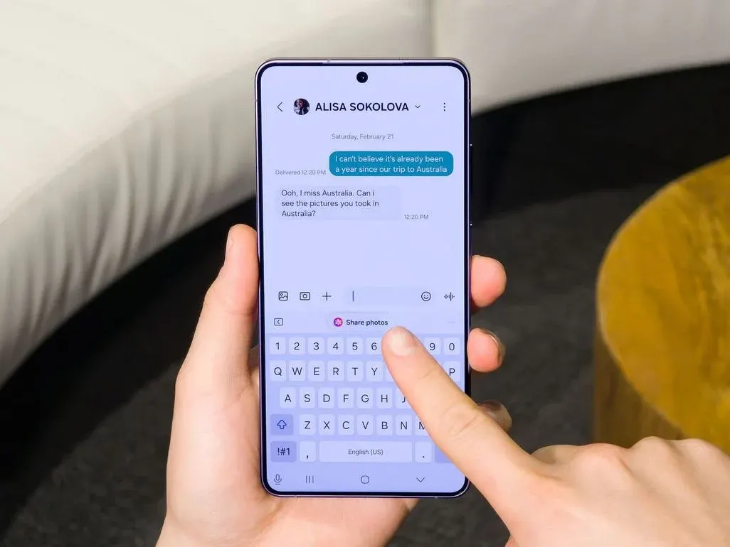 Person hält ein Smartphone mit geöffneter Messenger-App in der Hand und tippt mit dem Finger auf die Bildschirmtastatur, um eine Nachricht zu schreiben.