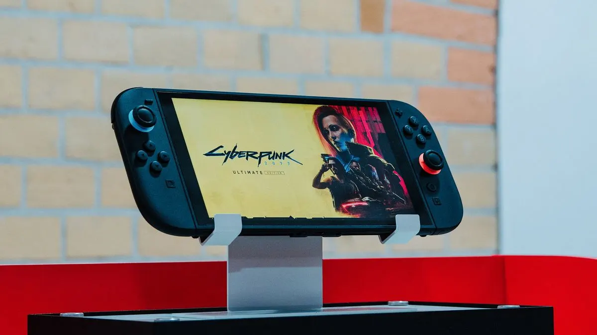 Nintendo Switch 2 Handheld-Konsole mit schwarzem Gehäuse steht auf einem Ständer und zeigt das Spiel Cyberpunk 2077 Ultimate Edition auf dem Display.