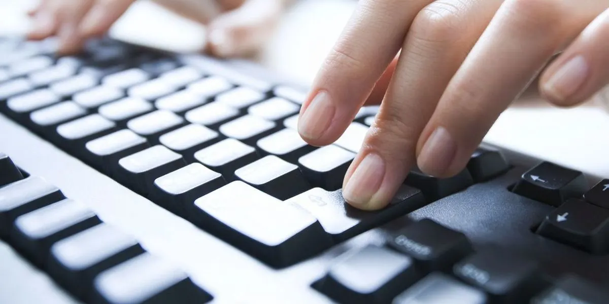Hände tippen auf schwarzer Computer-Tastatur in Nahaufnahme.