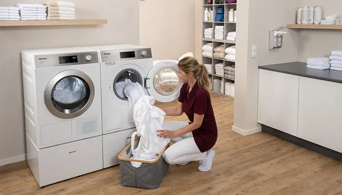 Eine Frau wäscht die Wäsche mit der Miele Pro Series Waschmaschine
