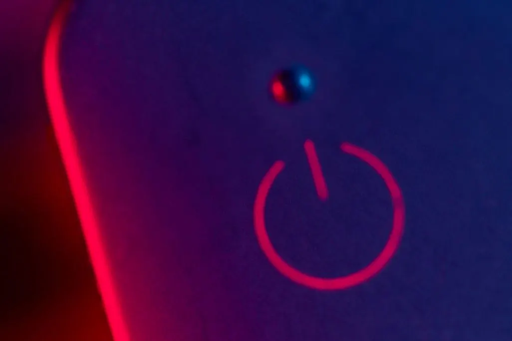 Rotes Power-Symbol leuchtet auf blau-violettem Hintergrund mit Lichteffekten
