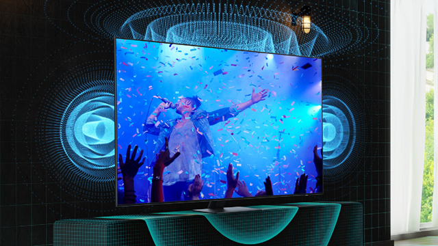 Ein Fernseher zeigt ein Konzert mit Konfetti und jubelnden Händen. Blaue Schallwellen umgeben das Gerät auf einem Tisch.