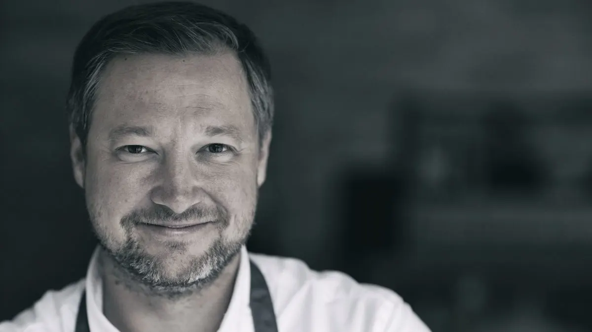 Portrait von Andreas Döllerer in schwarz-weiß mit unscharfen Hintergrund.