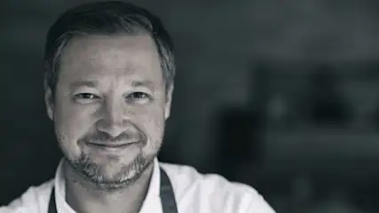 Portrait von Andreas Döllerer in schwarz-weiß mit unscharfen Hintergrund.
