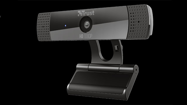 Eine schwarze Trust-Webcam steht auf einer Halterung. Die Kamera hat ein Lochmuster an den Seiten und ein HD-Objektiv in der Mitte.