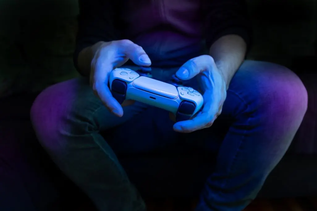 Nahaufnahme von Händen, die einen weißen PlayStation Controller halten