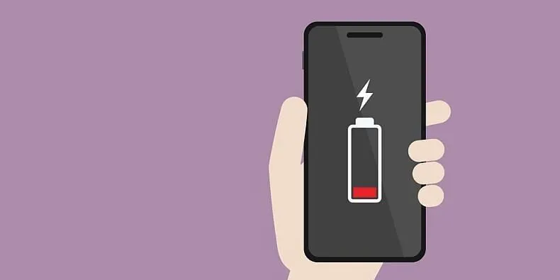 Hand haelt ein Smartphone mit Symbol fuer fast leeren Akku auf lila Hintergrund