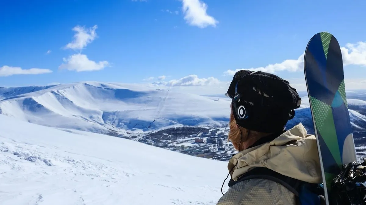 Skifahrer mit Kopfhoerern blickt auf verschneite Berglandschaft