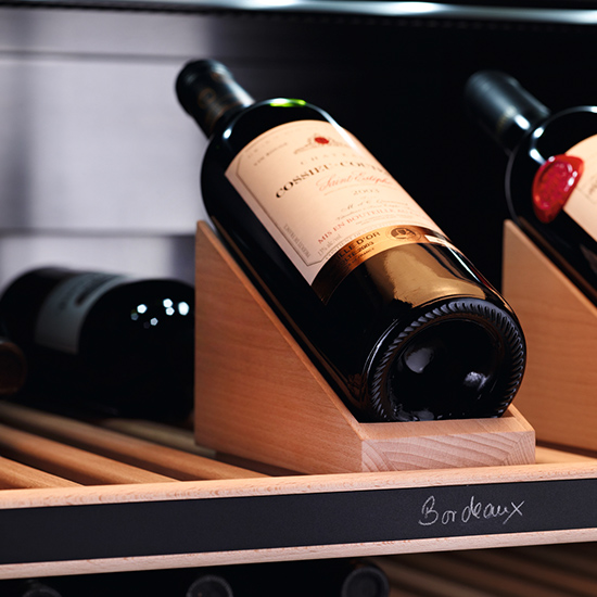 Mehrere Weinflaschen liegen auf Holzregalen. Die Beschriftung "Bordeaux" ist zu sehen.