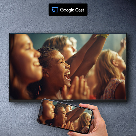 Ein Telefon spiegelt ein TV-Bild von feiernden Personen. "Google Cast"-Logo oben.