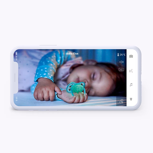 Handy-Display zeigt ein schlafendes Baby mit blauem Schnuller auf einem Bett. Auf dem Display sind Symbole zu sehen.