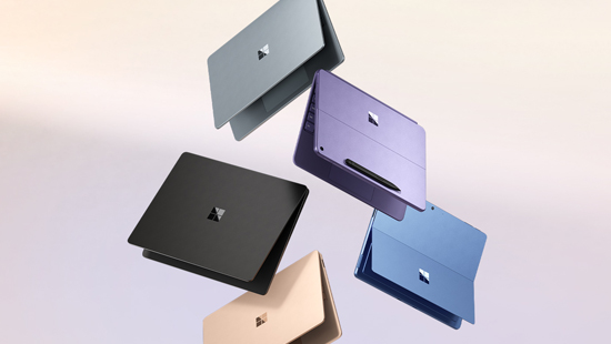 Fünf farbige Laptops, darunter Grau, Lila, Schwarz, Beige und Blau, schweben vor einem hellen Hintergrund.