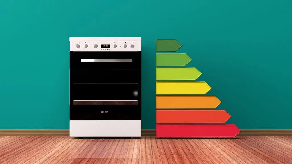 Weißer Elektroherd mit Energieeffizienzklassen-Labels von grün bis rot auf türkisem Hintergrund.