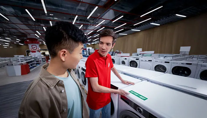 In einem Geschäft stehen weiße Waschmaschinen unter Neonlicht.